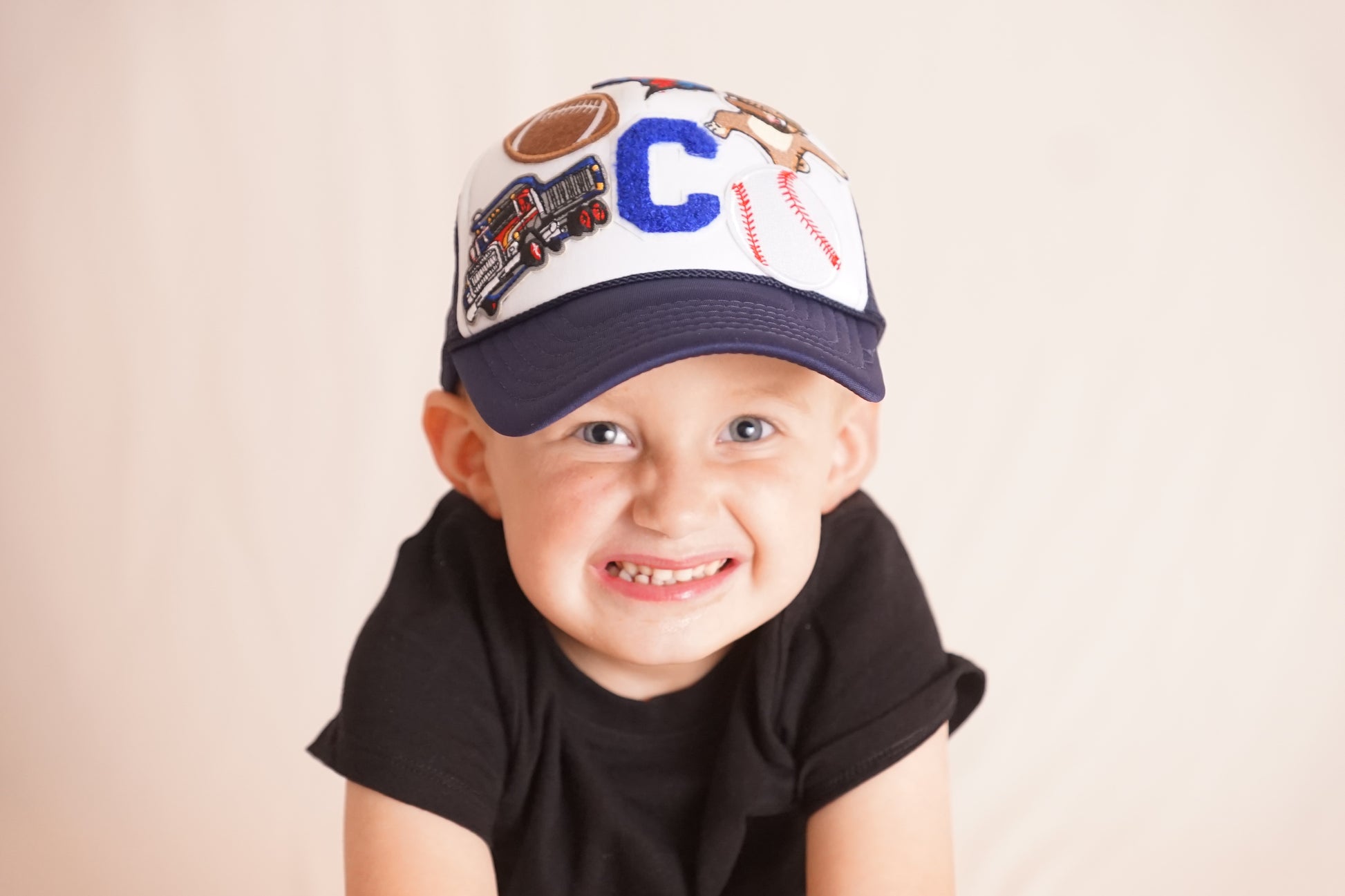Child wearing a cap with various symbols on a plain background