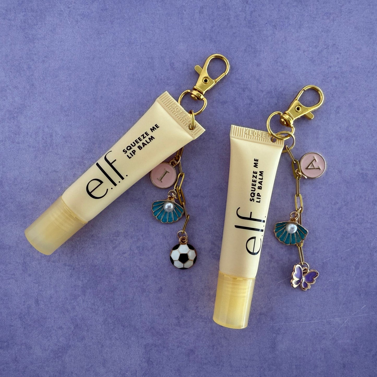 Two e.l.f. lip balm keychains with charms on a purple background