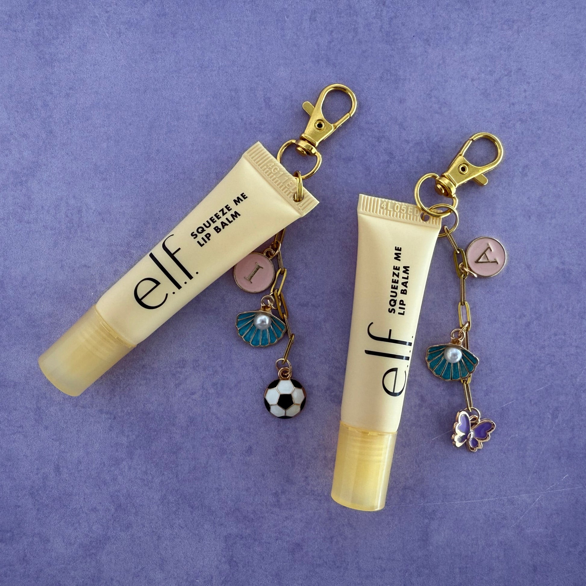 Two e.l.f. lip balm keychains with charms on a purple background