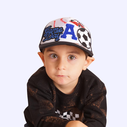 Child wearing a colorful 'Game Day' cap on a white background