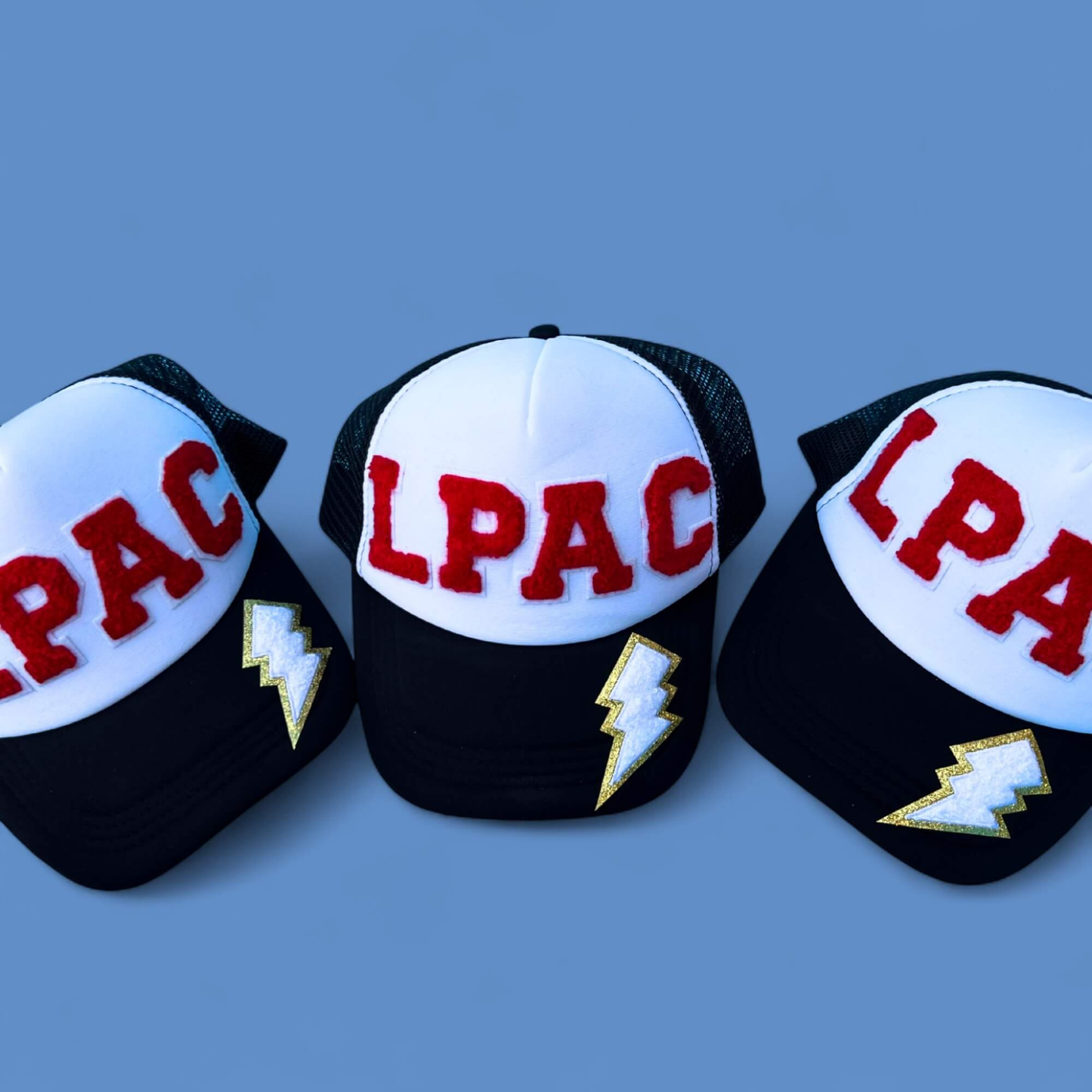 Three LPAC caps with lightning bolt designs on a blue background