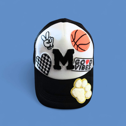 Black cap with various designs including a basketball, peace sign, and 'Good Vibes' text on a blue background.