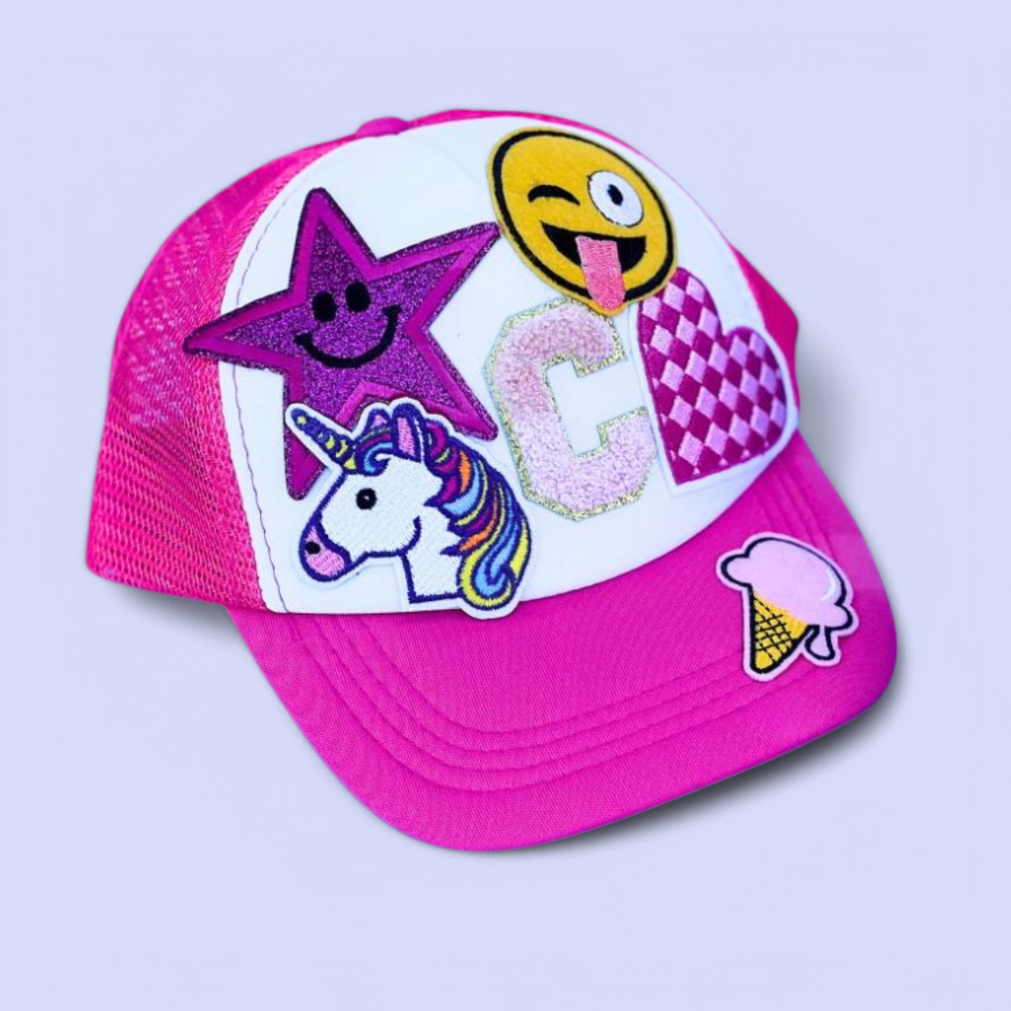 A pink personalized bucket hat with various colorful chenille patches including a star, a smiley face, a unicorn, and other designs.