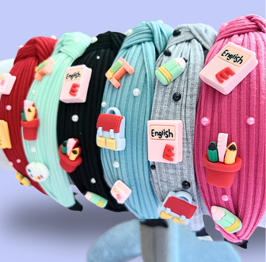 Set of colorful headbands with educational-themed decorations on a stand against a light purple background.
