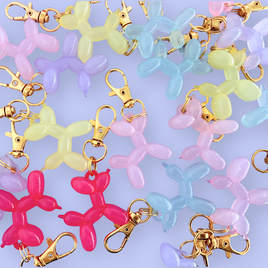 Colorful balloon dog keychains with gold clasp on a light blue background