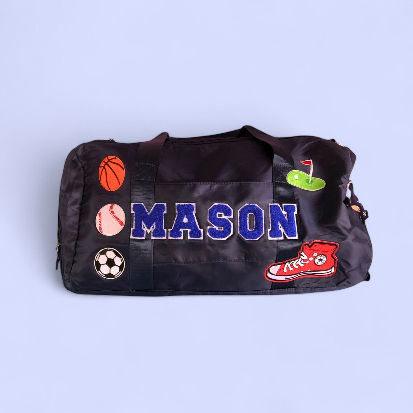 Black duffle bag with name “MASON” and sports patches 