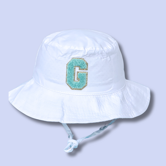White bucket hat with a turquoise letter 'G' on a light gray background