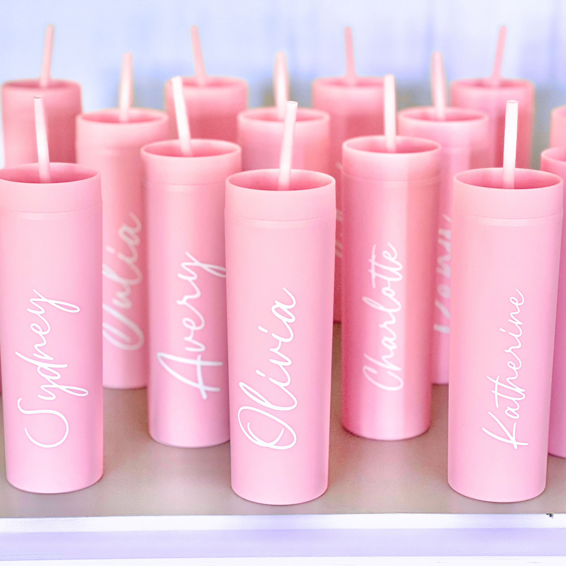 (Pink tumblers close-up):
A group of pink tumblers with white name decals like “Sophie,” “Chloe,” “Olivia,” and “Madison.”