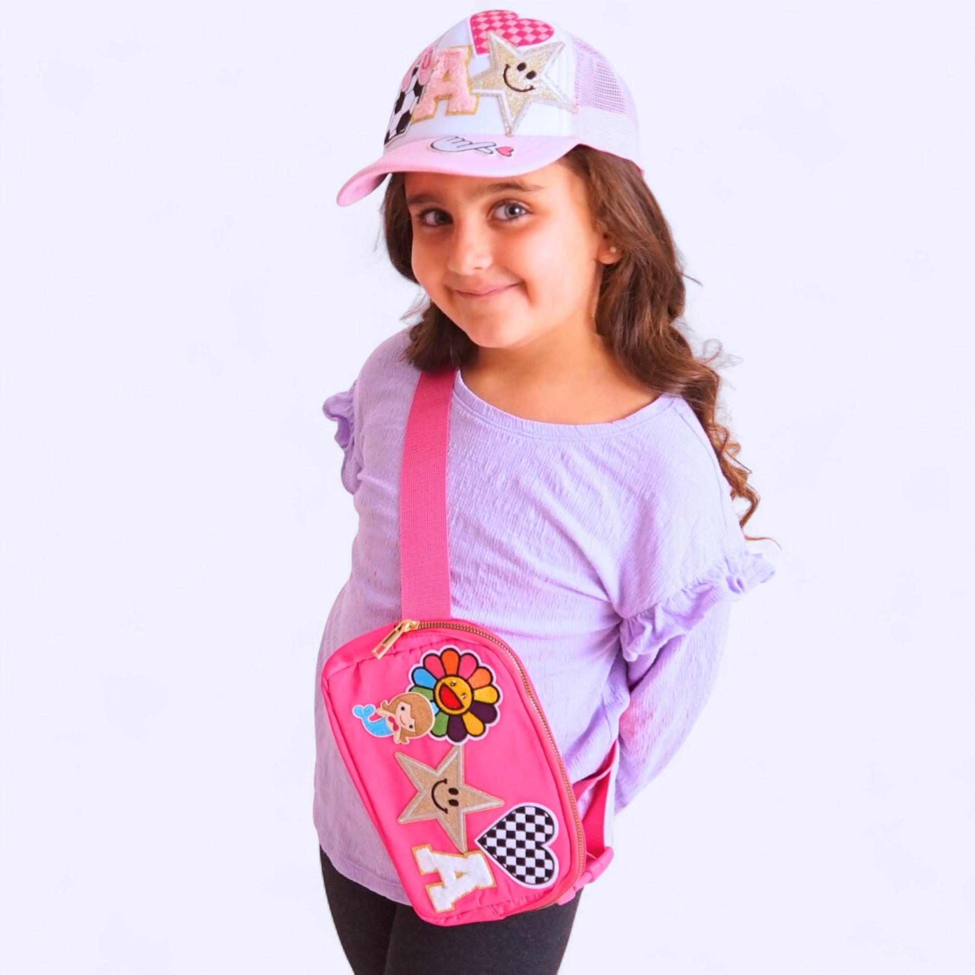 A hot pink sling bag with various embroidered patches,